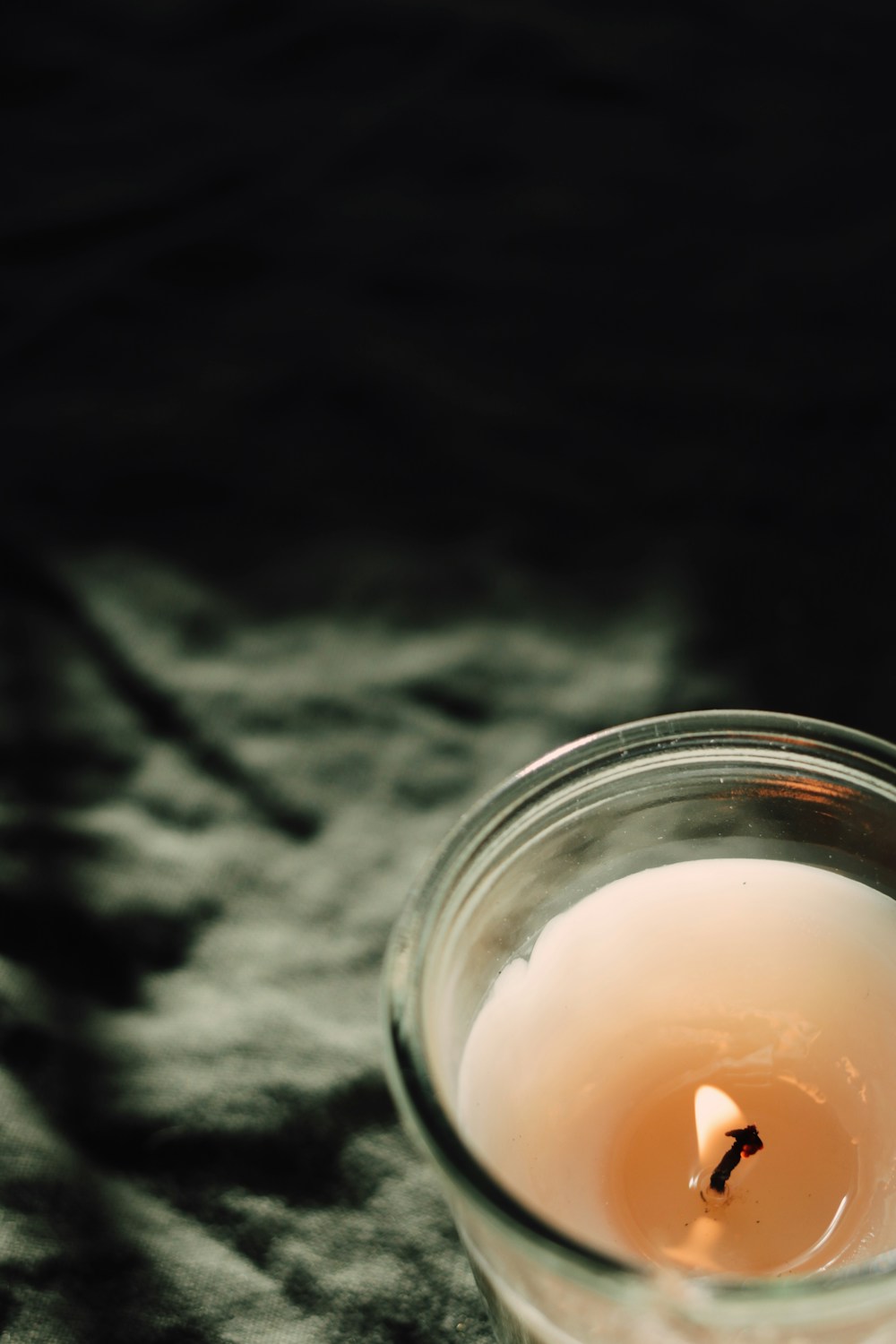 A candle glowing against olive green linen